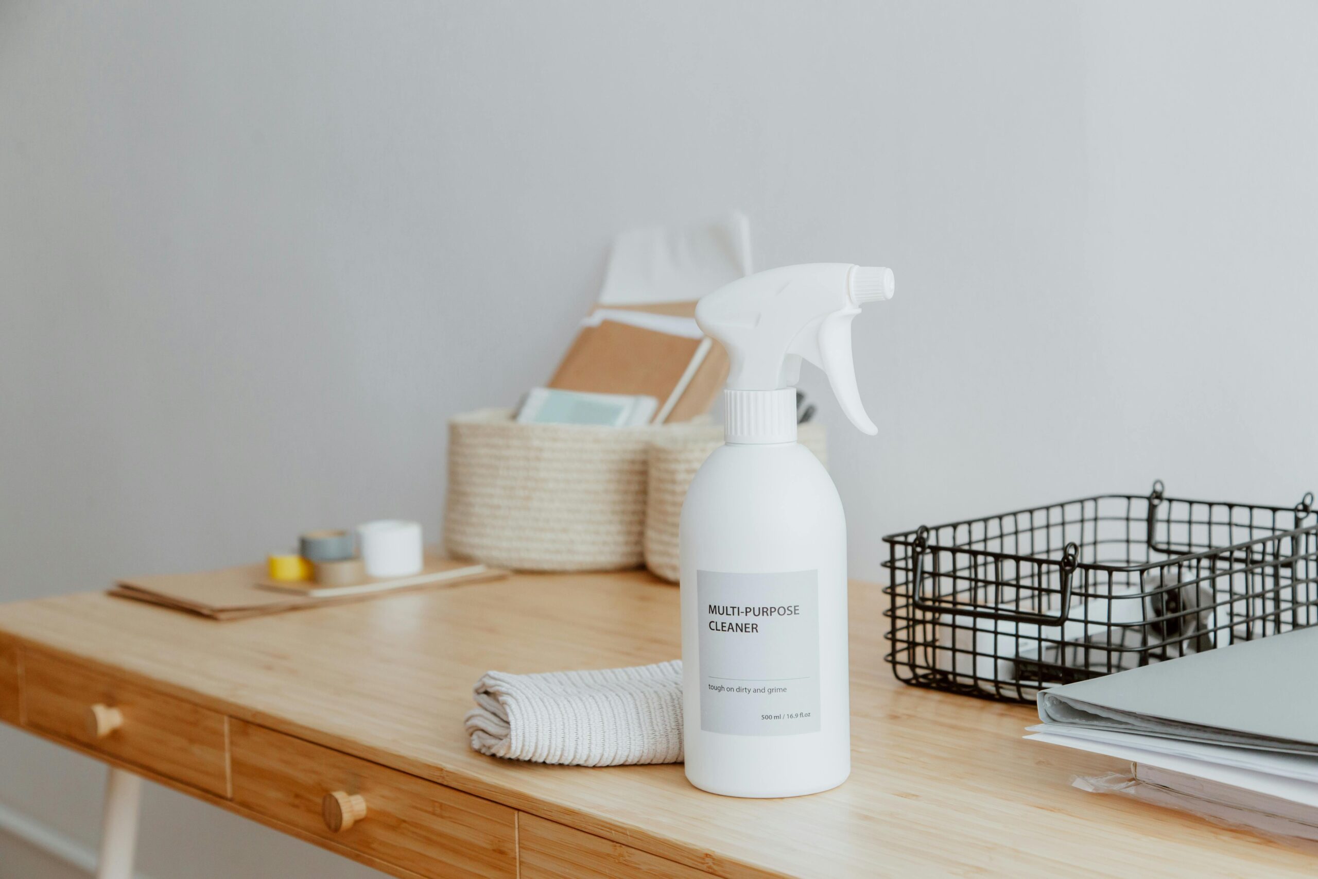 Home Minimalist desk with a focus on a multipurpose cleaner, office supplies, and storage solutions.